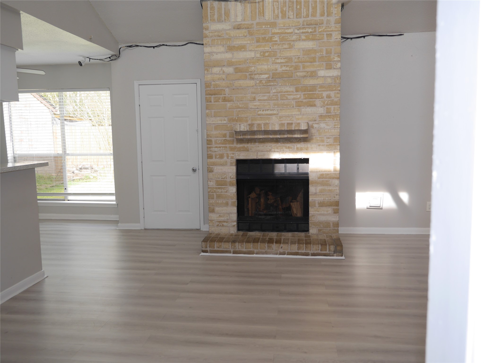 7410 Canasta Lane Houston, TX 77083 - Photo 14 of 33 an empty room with wooden floor a fireplace and windows