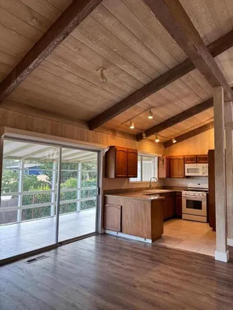 a view of a kitchen with wooden floor and stainless steel appliances