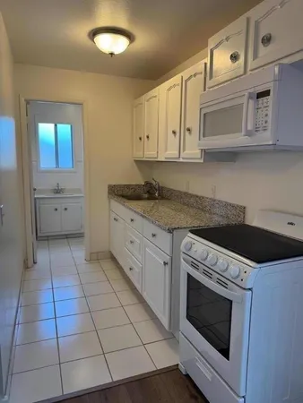 a kitchen with granite countertop white cabinets stainless steel appliances and sink