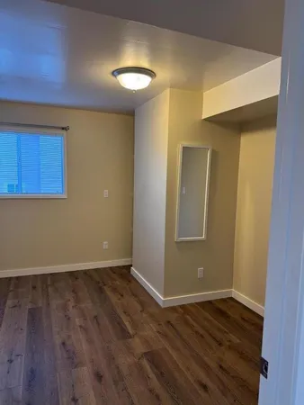 a view of an empty room with wooden floor and closet