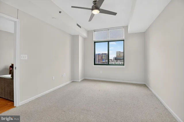 an empty room with windows and fan