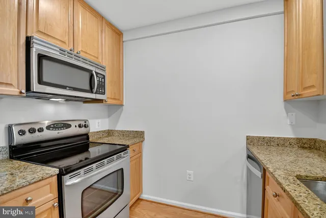 a kitchen with granite countertop cabinets stainless steel appliances and a window