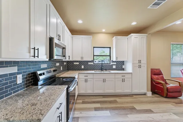 a kitchen with stainless steel appliances granite countertop a sink stove and refrigerator