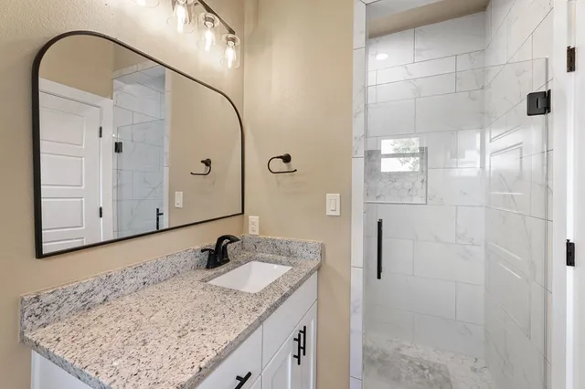 a bathroom with a granite countertop sink and a mirror