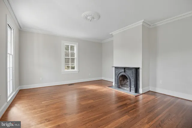 a view of empty room with a fireplace and wooden floor