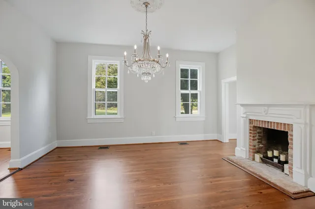 an empty room with wooden floor fireplace and windows