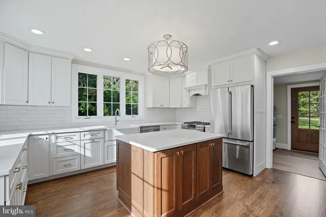 a kitchen with stainless steel appliances granite countertop a refrigerator a sink dishwasher a stove and white cabinets with wooden floor