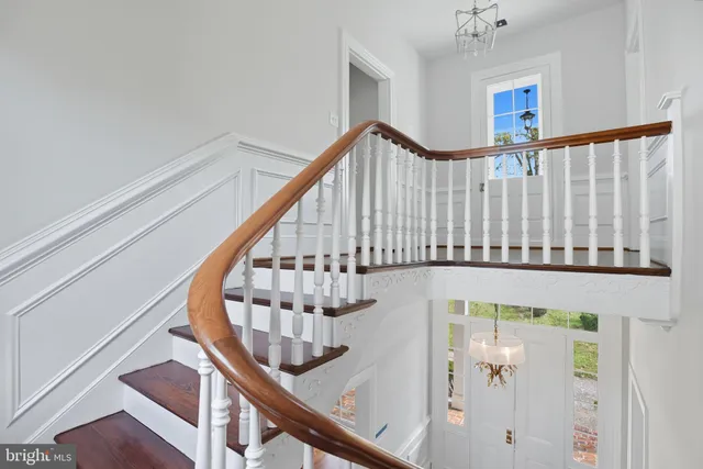a view of a hallway with wooden floor and chandelier