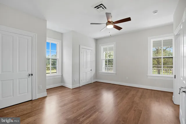 an empty room with wooden floor fireplace and windows
