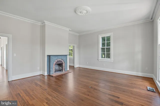 an empty room with wooden floor fireplace and windows