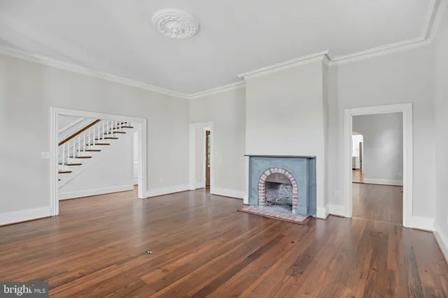 an empty room with wooden floor fireplace and windows
