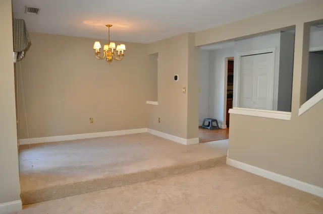 a view of an empty room with a chandelier fan