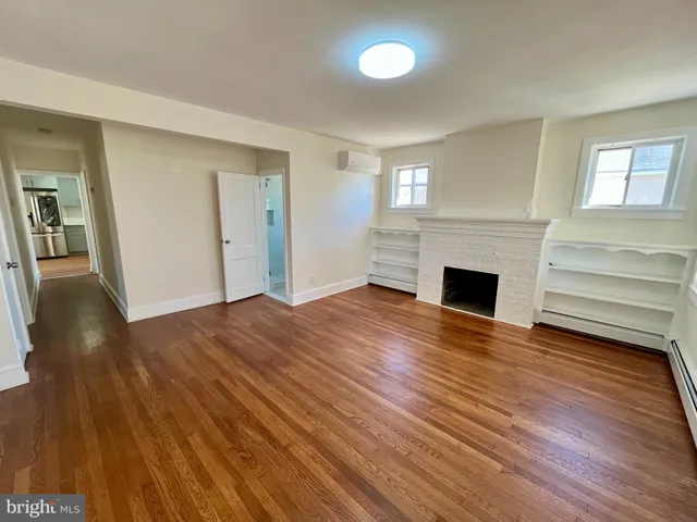 a view of empty room with wooden floor and fireplace