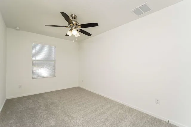 an empty room with a window and a fan