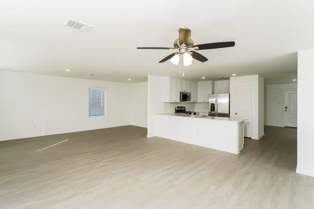 a view of kitchen with kitchen island stainless steel appliances wooden floor cabinets and a potted plant