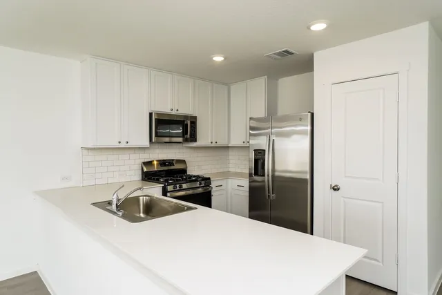 a kitchen with kitchen island a sink stainless steel appliances and cabinets