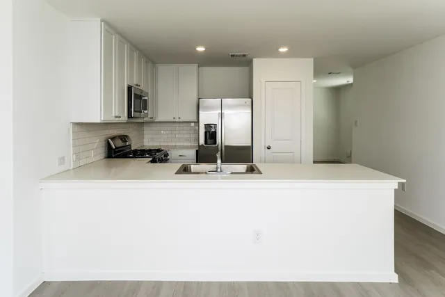 a room with a sink a refrigerator and cabinets