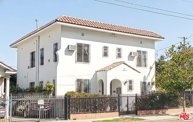 a view of a white house with iron fence