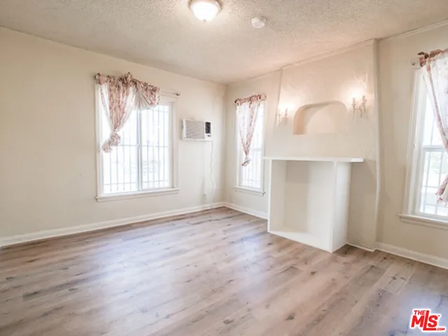 an empty room with wooden floor cabinet and windows