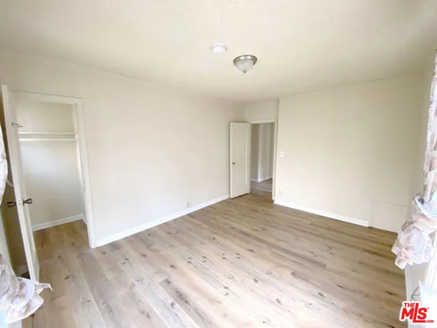 an empty room with wooden floor and bathroom