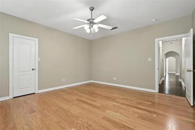 an empty room with chandelier fan and windows