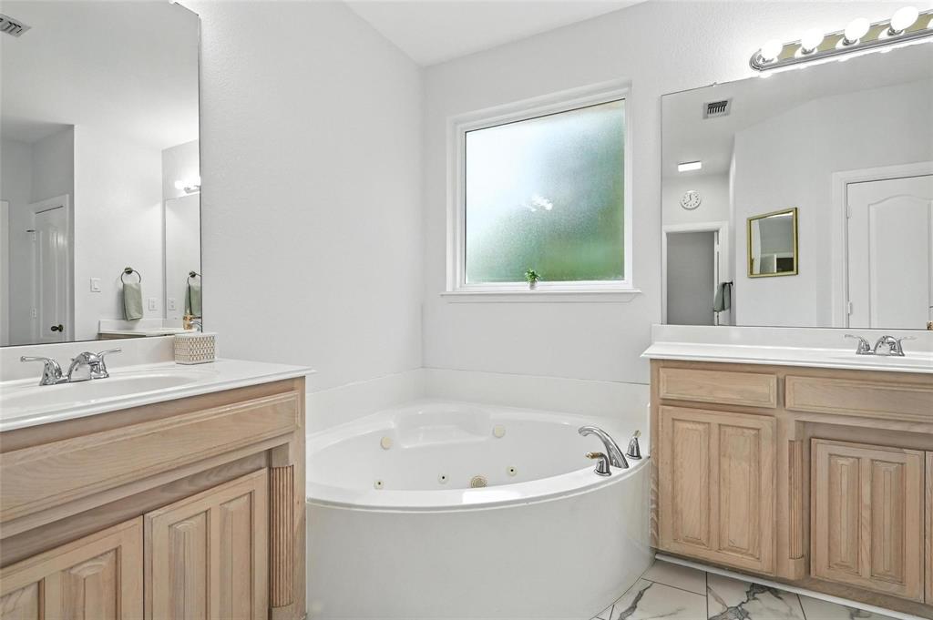 8974 Ranch Bluff Court Benbrook, TX 76126 - Photo 18 of 37 a bathroom with a bathtub a mirror a double vanity sink and mirror