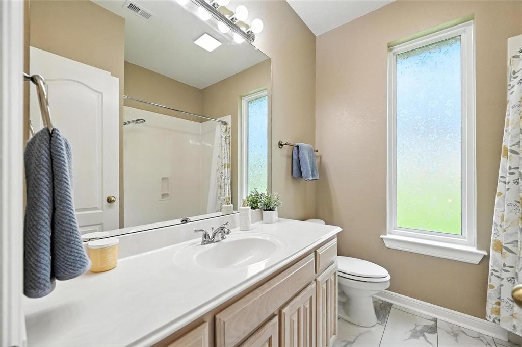 8974 Ranch Bluff Court Benbrook, TX 76126 - Photo 22 of 37 a bathroom with a sink a toilet a mirror and a window
