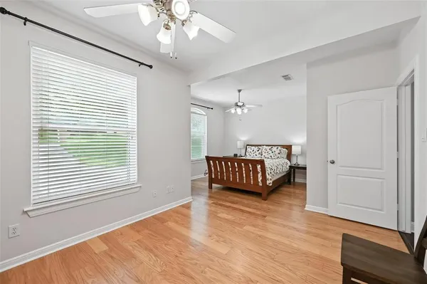 a spacious bedroom with a bed window and wooden floor