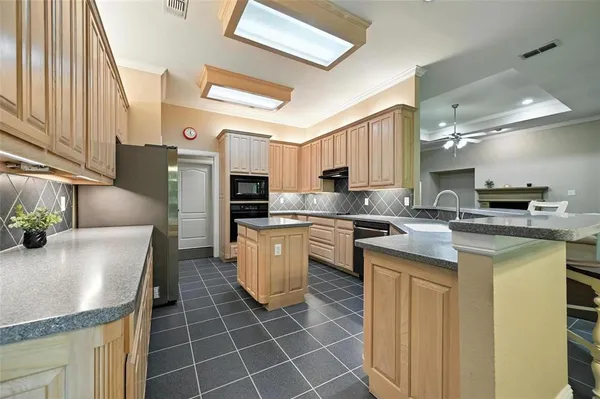 a kitchen with stainless steel appliances granite countertop a sink a stove a refrigerator a microwave oven with white cabinets and wooden floor