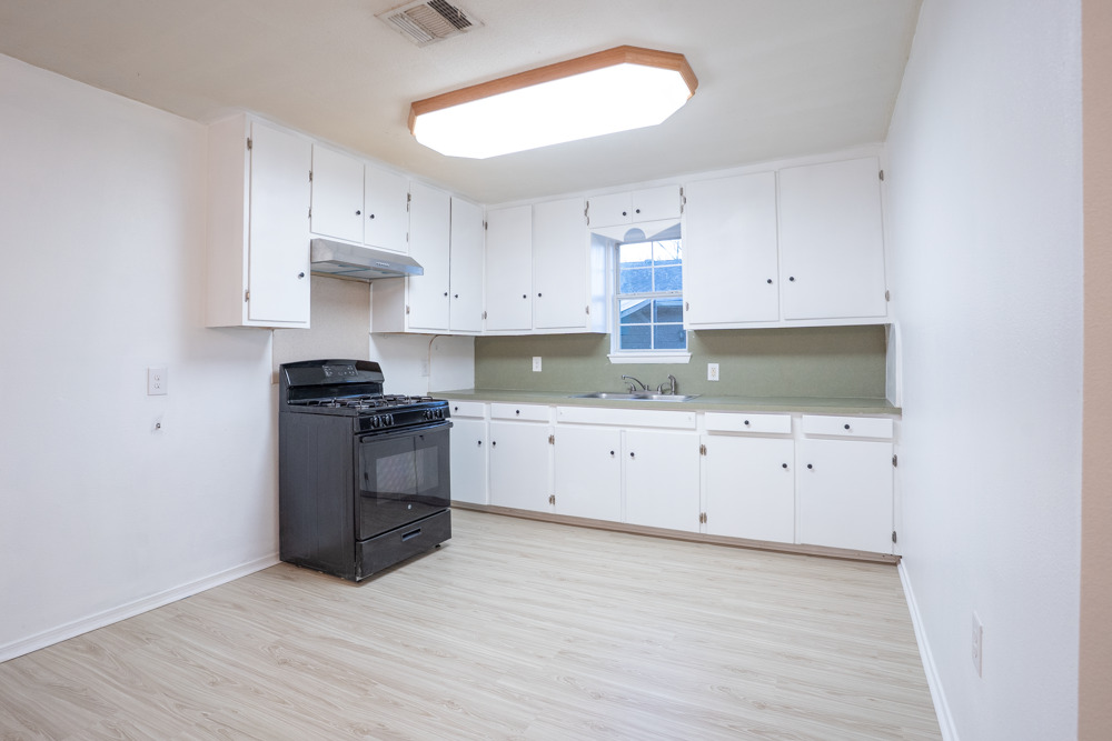 207 Harris Street Elgin, TX 78621 - Photo 11 of 19 a kitchen with granite countertop white cabinets and stainless steel appliances