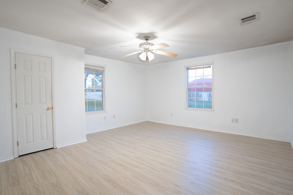 207 Harris Street Elgin, TX 78621 - Photo 12 of 19 an empty room with wooden floor ceiling fan and windows