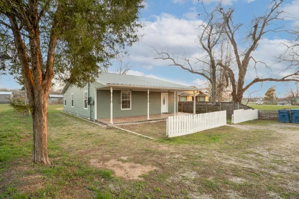 a view of house with yard and trees in the background