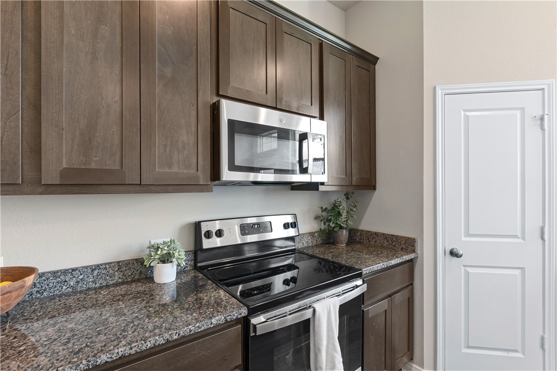 4746 Holm Oak Road College Station, TX 77845 - Photo 12 of 25 a kitchen with granite countertop a stove a microwave and cabinets