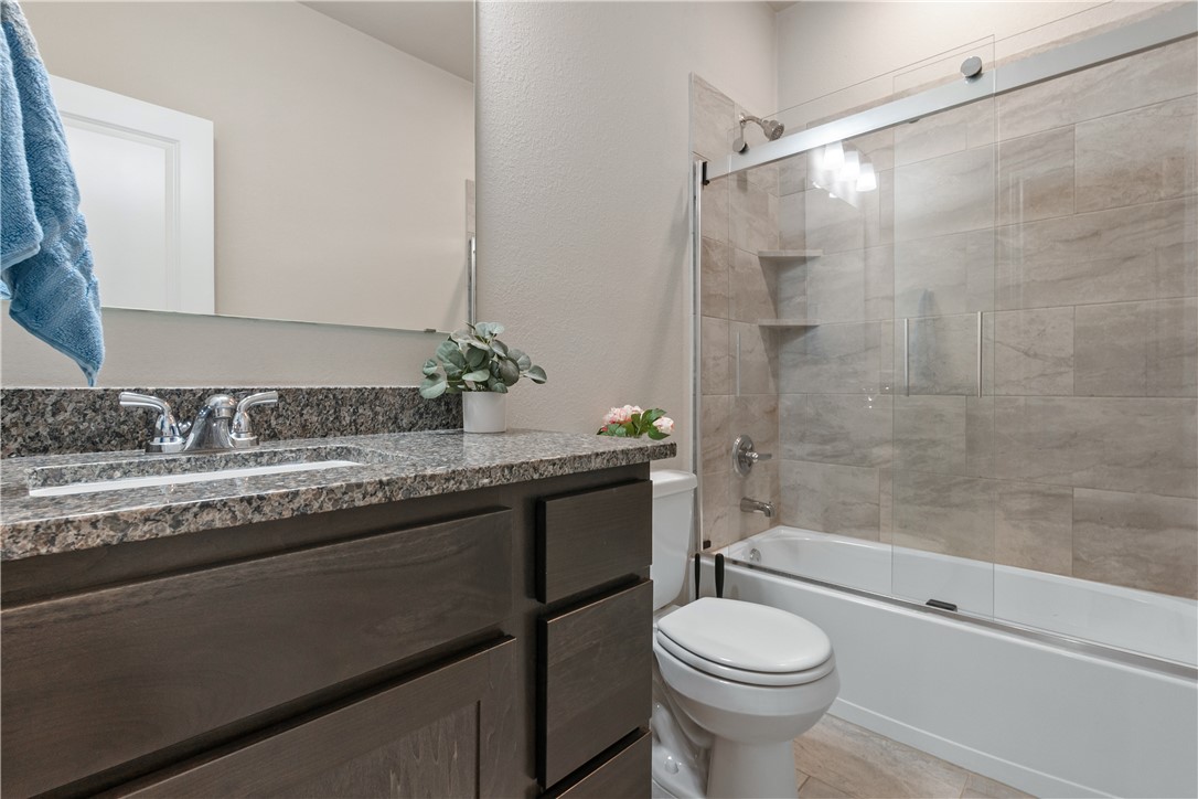 4746 Holm Oak Road College Station, TX 77845 - Photo 18 of 25 a bathroom with a granite countertop toilet sink and shower