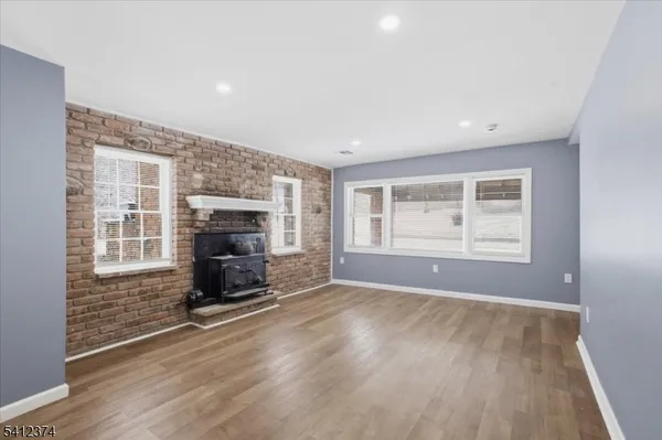 an empty room with windows fireplace and wooden floor