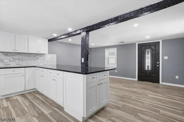 a kitchen with granite countertop white cabinets and wooden floor