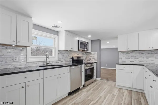 a kitchen with stainless steel appliances granite countertop a sink and cabinets with wooden floors
