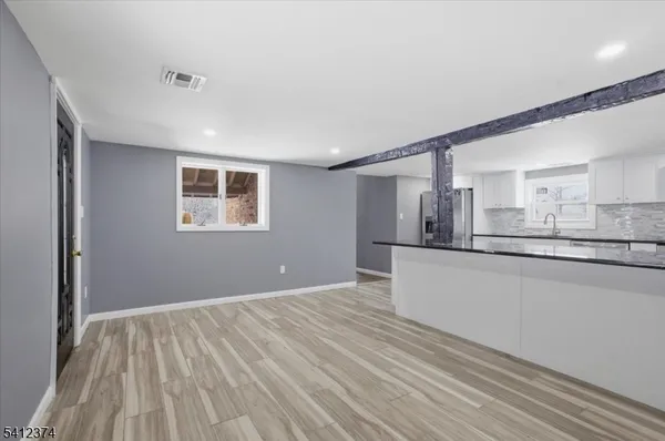a view of kitchen and empty room with wooden floor