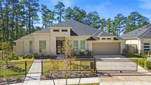 a front view of house with yard outdoor seating and covered with trees in the background