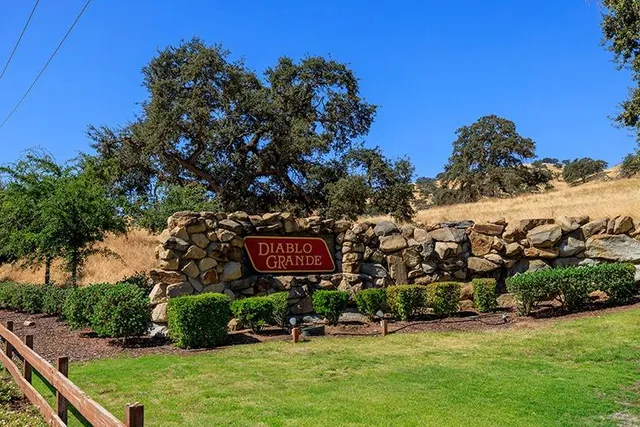 a sign that is sitting in front of a house with a yard