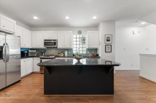 a kitchen with kitchen island a sink dishwasher a refrigerator and a stove with wooden floor