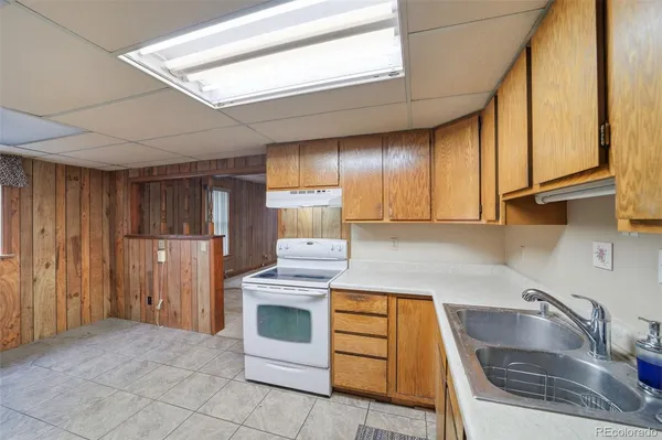 a kitchen with granite countertop a sink a stove and refrigerator