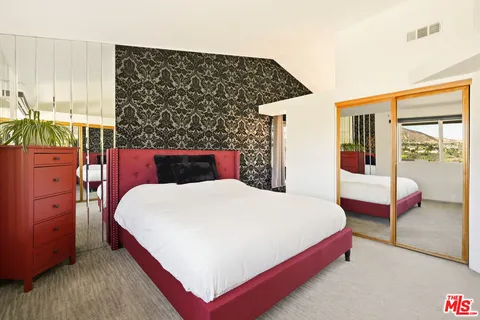 a bed sitting in a bedroom next to a window with dresser