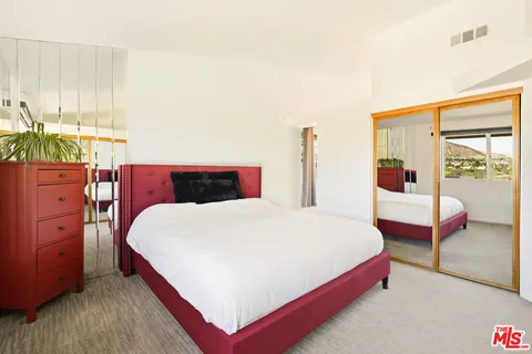 a bedroom with a large bed and wooden floor