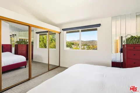 a bedroom with a bed and dresser with mirror