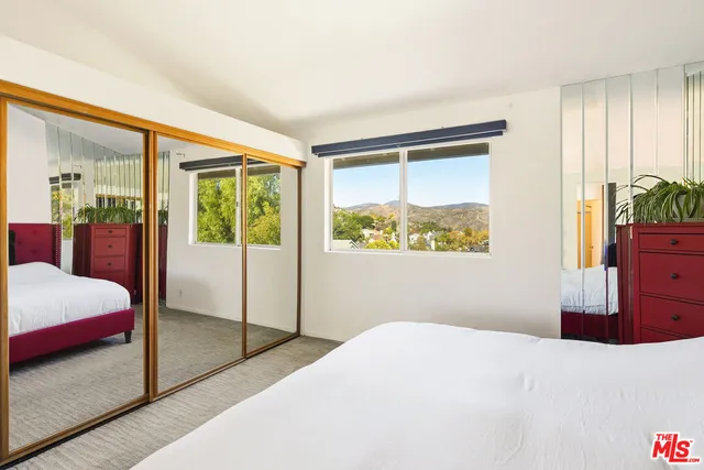 a bedroom with a bed and dresser with mirror