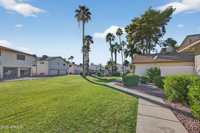 a view of a house with a yard and palm trees