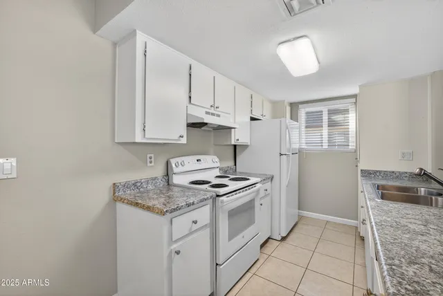 a kitchen with granite countertop a sink stove and cabinets