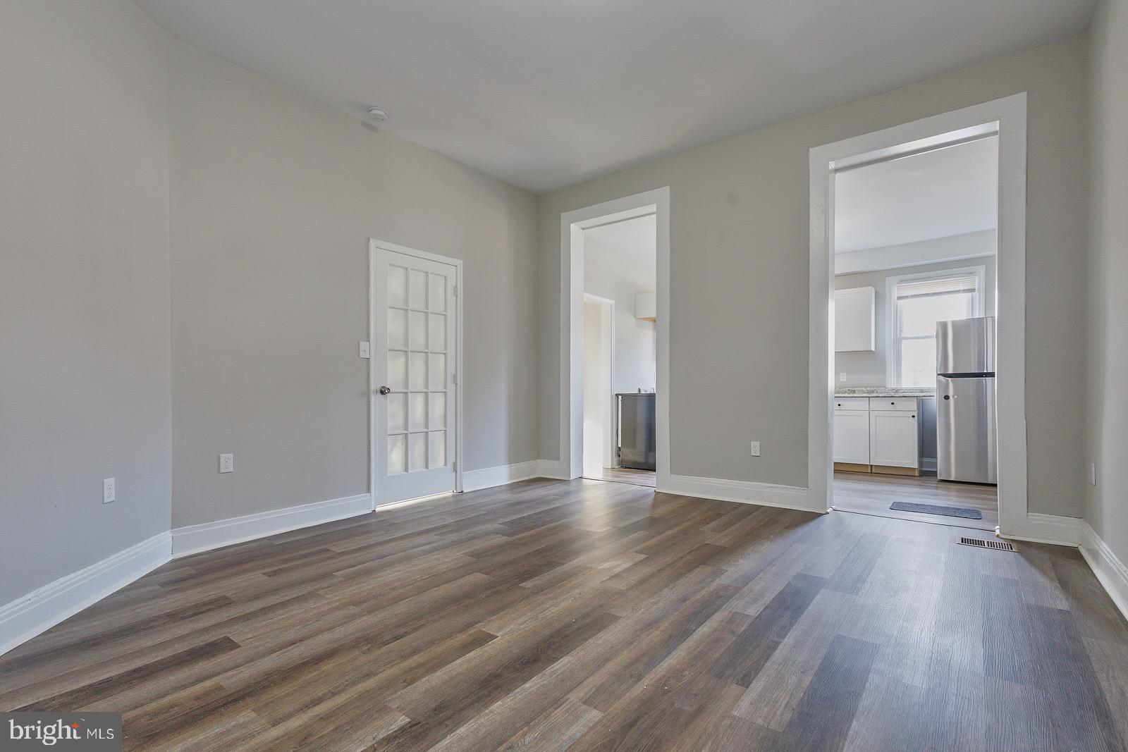 3407 Elgin Avenue, Unit 1 Baltimore, MD 21216 - Photo 7 of 15 an empty room with wooden floor & windows and bathroom