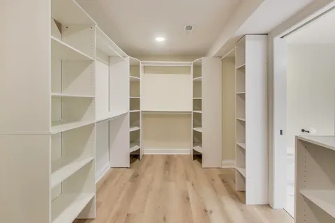 a view of an empty room with chandelier and wooden floor